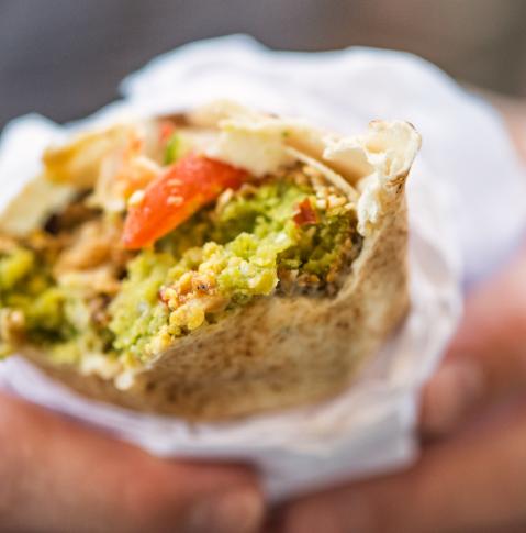 ein Mann hält Falafel Mahshi in einem Khubz Pita Wrap